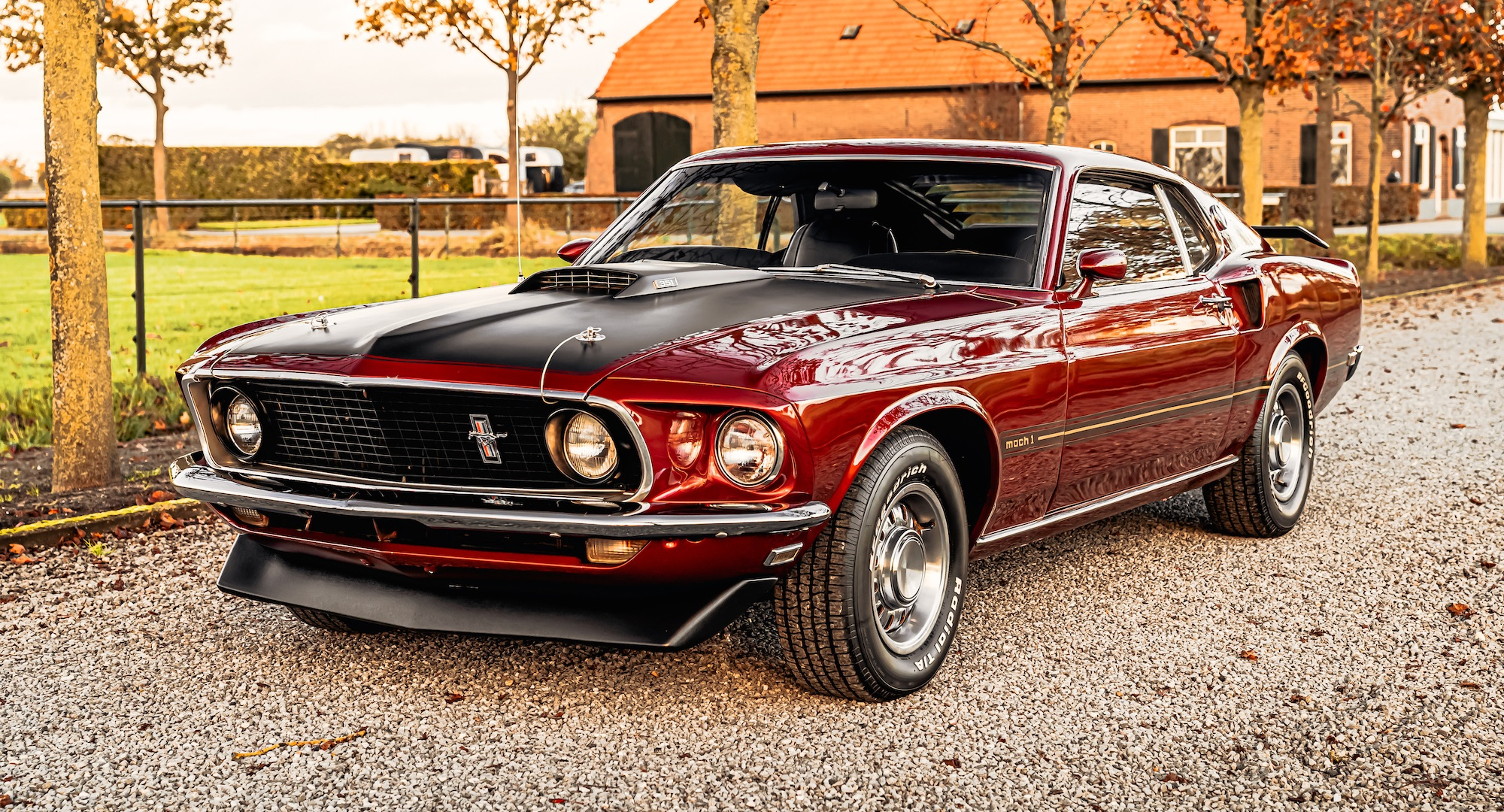Red classic Mustang fastback parked on a gravel drive